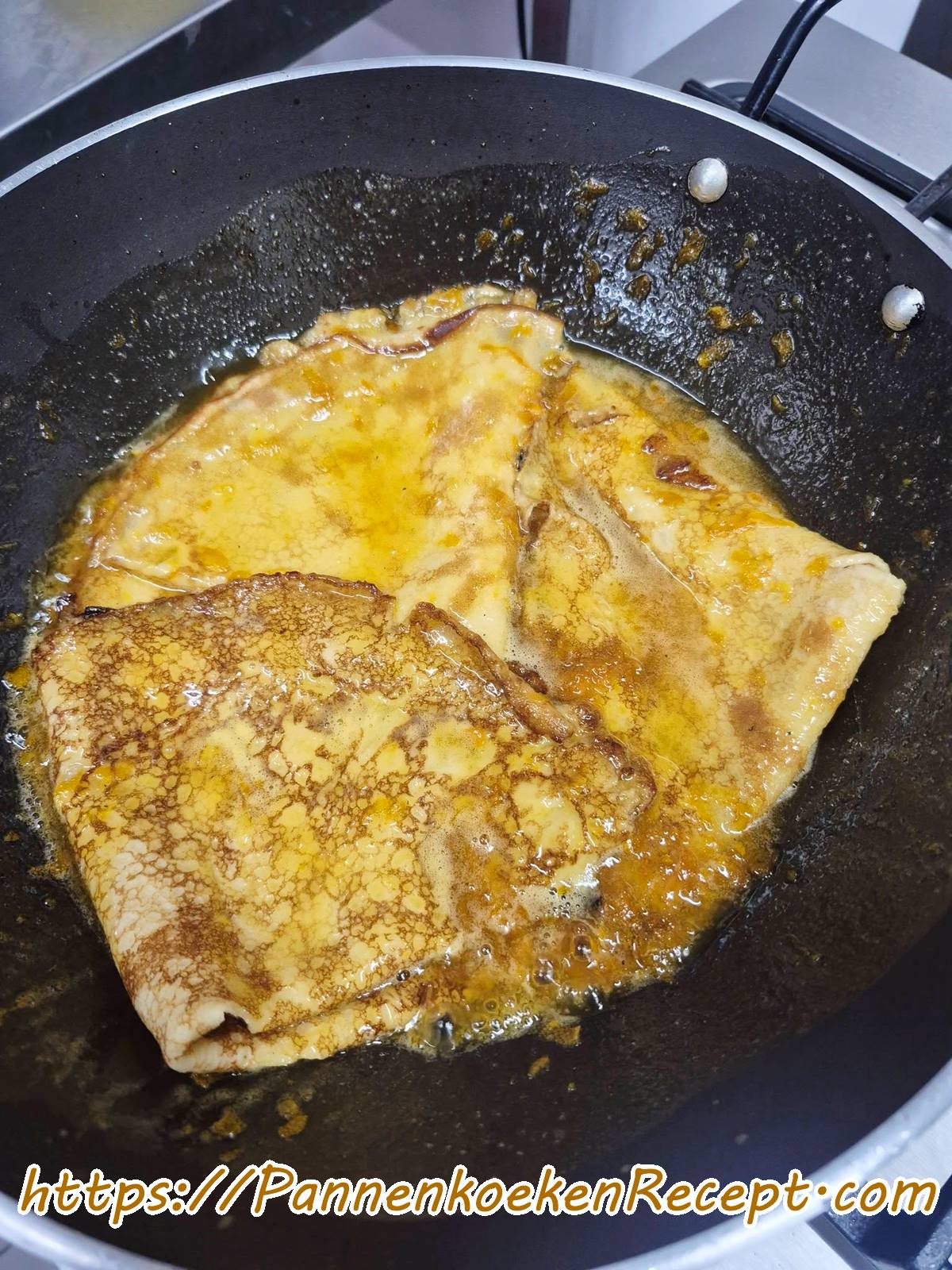 Gevouwen pannenkoeken die opwarmen in sinaasappelsaus voor Crêpes Suzette